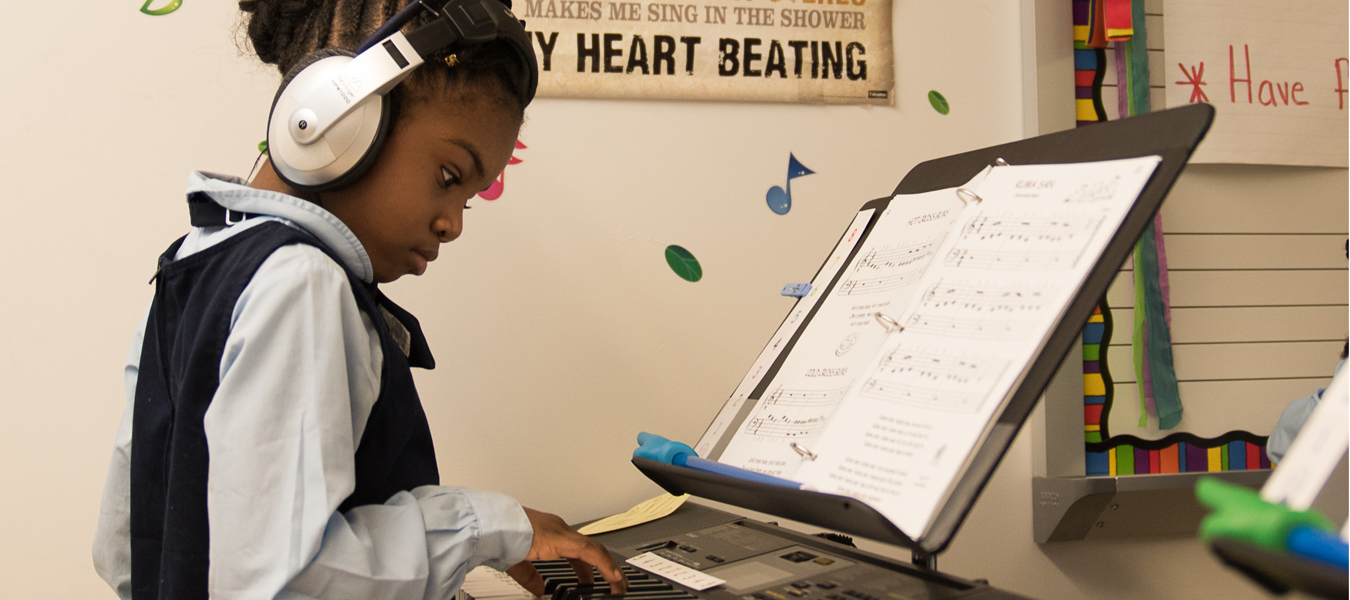 A young girl concentrates on her sheet music as she practices piano independently.
