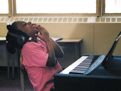 A photo from the early 90s shows a young girl seated at the piano and throwing her head back in laughter.